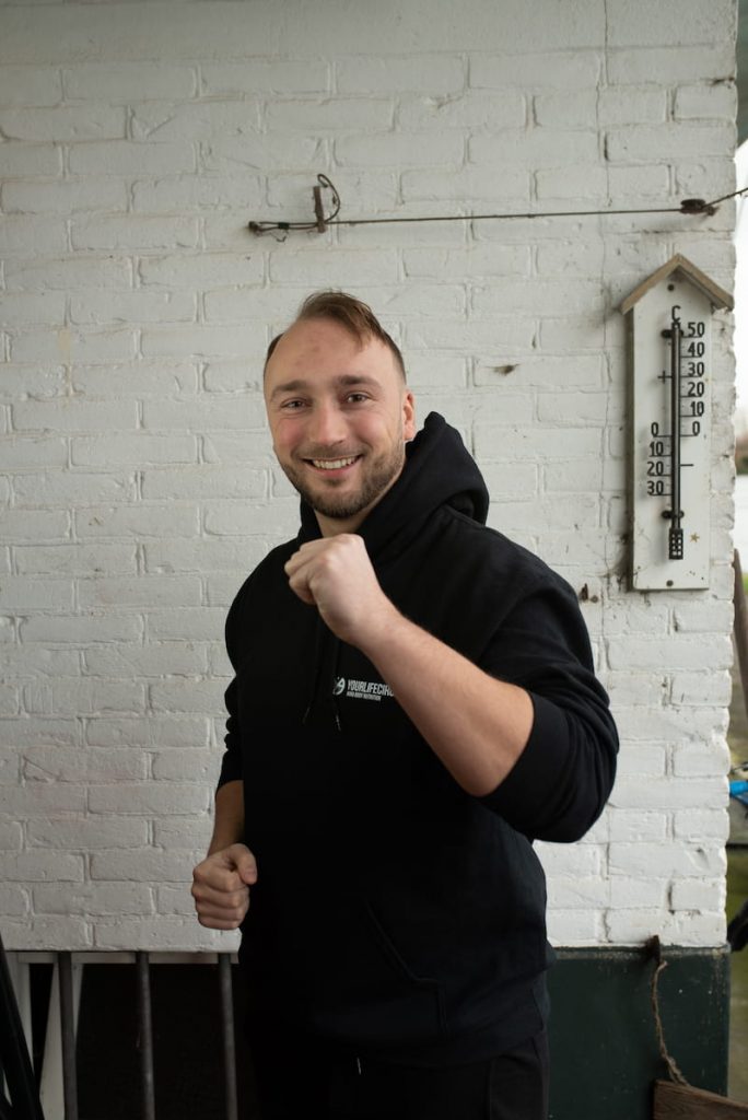 Personal trainer Jeroen staat vrolijk met zijn vuist vooruit