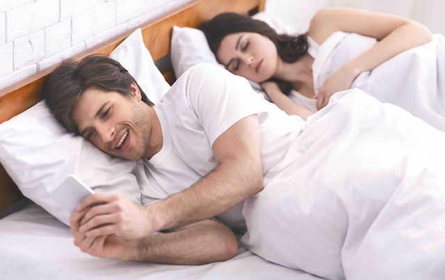 koppel waarbij de man porno kijkt in bed naast elkaar. 
