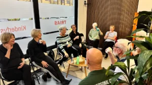 Rond de 10 mensen die gezellig in een kring lachen en koffie drinken