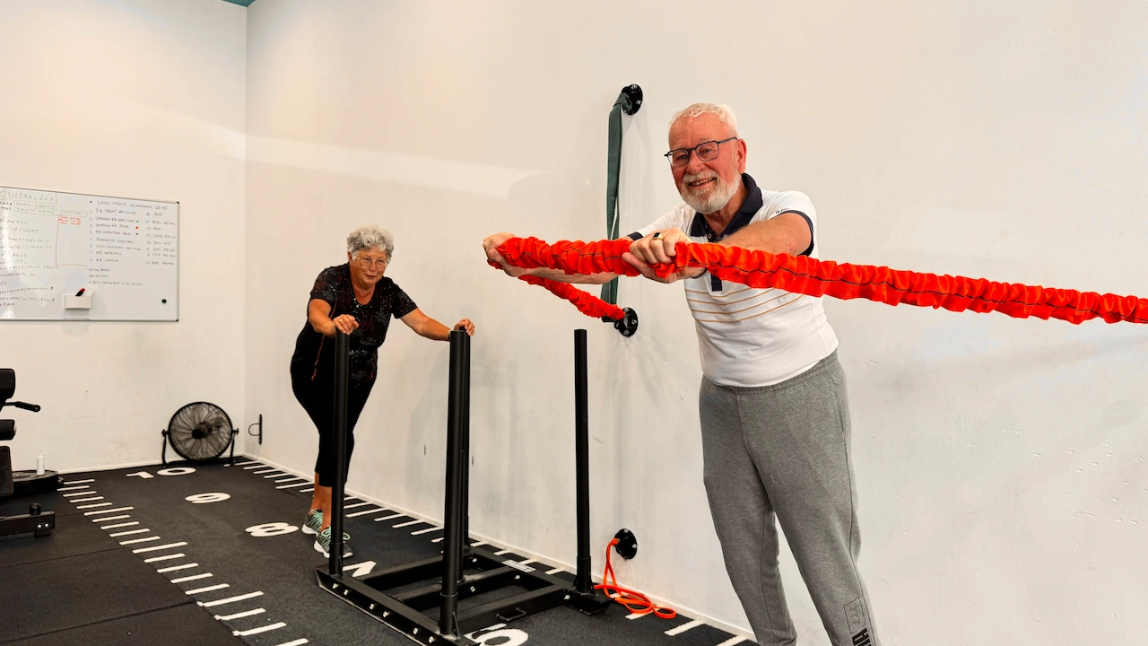 koppel samen aan het sporten. vrouw duwt de slee en man duwt touw naar voren
