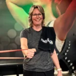 Klant Leonie doet lachend schouder oefening met elastiek.