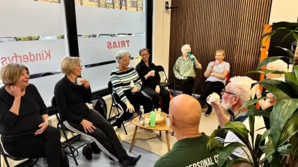 Rond de 10 mensen die gezellig in een kring lachen en koffie drinken